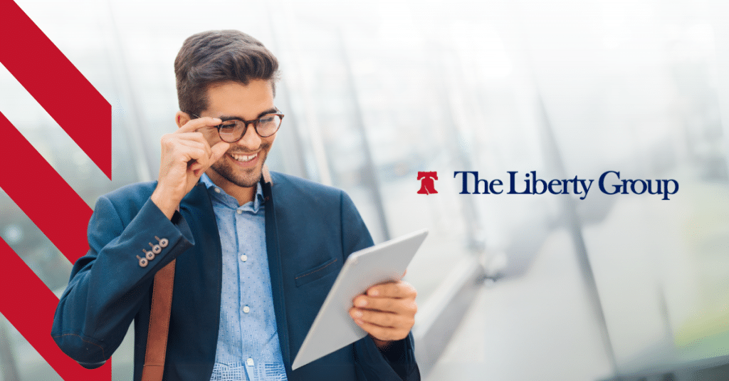 A man in a blazer adjusts his glasses while looking at a tablet; The Liberty Group logo is displayed on the right.