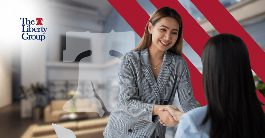 A woman smiling as she shakes another woman's hand; The Liberty Group logo is in the top left corner.