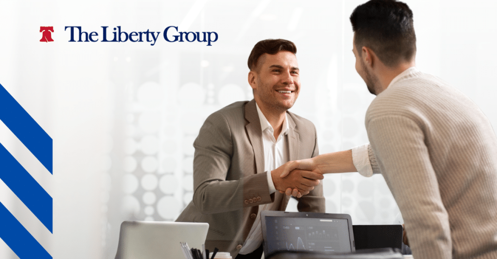 Two professionals shaking hands across a desk, symbolizing a successful job placement.