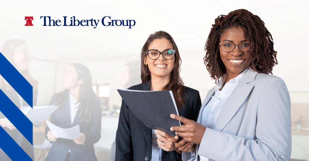 Two professional women in business attire smiling while reviewing documents.