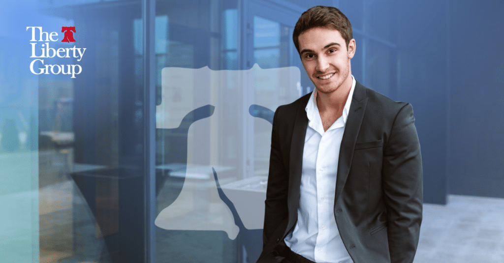 A professionally dressed man smiling in a modern office setting